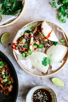 two bowls filled with food next to some dipping sauces and lime wedges on the side