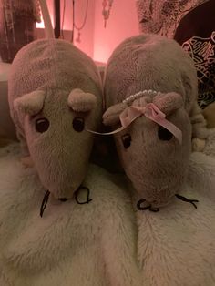 two stuffed animals laying on top of a bed next to each other in front of a pink light