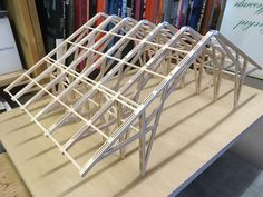 a wooden structure sitting on top of a table next to a book shelf filled with books