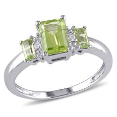 Put the finishing touch on a luxurious look with this lovely ring featuring an emerald-cut prong-set center stone peridot and 2 baguette-cut prong-set peridot gemstones with 2 round-cut shared prong-set white diamonds crafted in 10-karat white gold. This elegant ring is enhanced with a high-polish finish. The diamonds total 1/20ctw and are G or better in color and I1 or better in clarity. The ring measures 12.8mm in length by 7.5mm in width by 6.6mm in thickness. Stone Ring Design, 3 Stone Rings, Three Stone Ring, Sparkling Rings, Ring With Diamond, Peridot Ring, Peridot Gemstone, August Birth Stone, Three Stone Rings