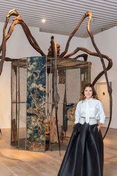 a woman standing in front of a giant spider sculpture with her hands on her hips