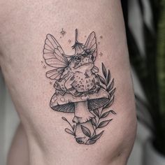 a black and white tattoo of a fairy on the thigh, with a frog sitting on top of a mushroom