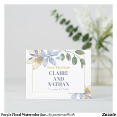 save the date card with blue flowers and greenery in vase on white tablecloth