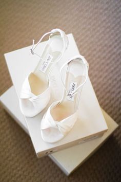 two pairs of white shoes sitting on top of a box