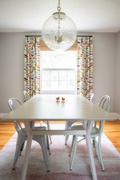 a dining room table with chairs and a chandelier hanging from it's ceiling