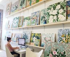 two screenshots of paintings on the wall above a desk with a person sitting at a computer in front of them