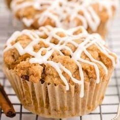 muffins with icing and cinnamon on a cooling rack next to two cinnamon sticks