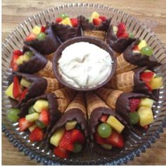 a glass plate topped with fruit and chocolate covered pastries on top of a wooden table