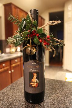 a bottle of wine sitting on top of a counter next to a christmas wreath and holly