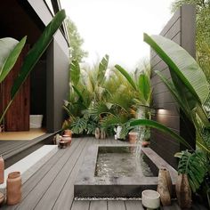 an outdoor water feature in the middle of a wooden decked area with potted plants