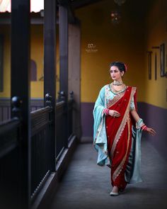 a woman in a red and blue sari is walking down the street with her hand on her hip