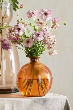 two vases with flowers in them sitting on a table next to each other,