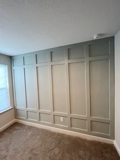 an empty room with white paneled walls and carpet