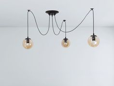 three light fixtures hanging from the ceiling in a room with white walls and flooring