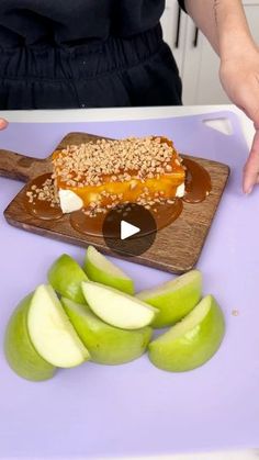 a person standing in front of a cutting board with sliced apples and caramel on it