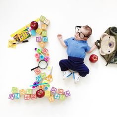 a baby laying on the floor next to toys and letters that spell out the letter e