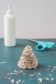 a pine cone christmas tree sitting on top of a table next to scissors and a bottle