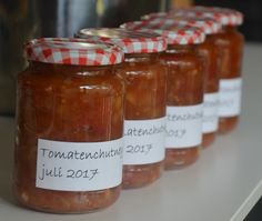 four jars of tomato sauce are lined up on a counter top with labels that read tomatoatenoulie, july 2017