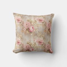 a pink flowered pillow on a white wall with a wooden frame in the background