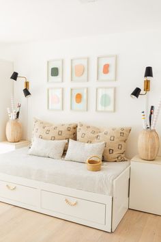 a white bed sitting in a bedroom next to two lamps and pictures on the wall