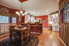 a dining room and kitchen area with hardwood floors, red walls, and white cabinets