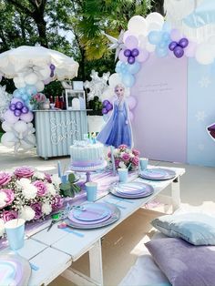 a frozen princess themed birthday party with balloons, cake and flowers on a table in front of a backdrop