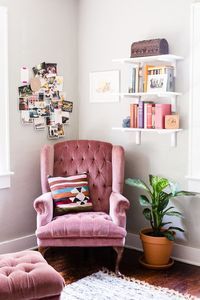 a pink chair sitting in front of a white wall