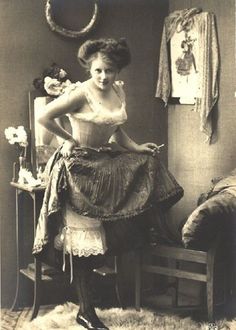 an old photo of a woman sitting on a chair with her hands on her hips