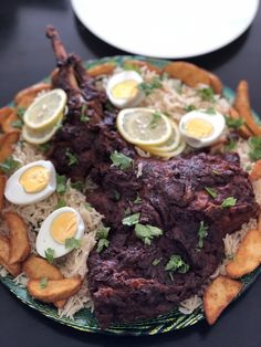 a plate topped with meat and fried eggs on top of rice next to potato wedges