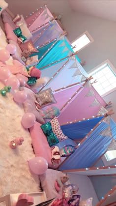 a room filled with lots of pink and blue balloons on top of a white floor