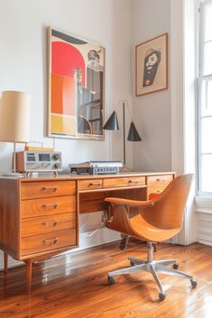 an office with a desk, chair and pictures hanging on the wall above it's windows