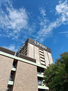 a tall brick building with the words unsw written on it's side and trees in front