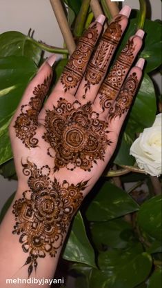 a woman's hand with henna on it and some flowers in the background