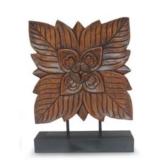 a carved wooden object with leaves on it's sides and a flower in the center