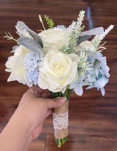 a person holding a bouquet of white and blue flowers