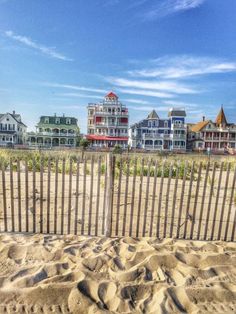 the beach is fenced off with sand and houses in the background