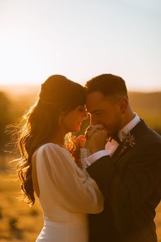 a bride and groom standing close to each other in front of the sun at their wedding