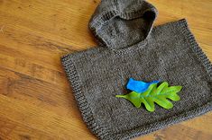 a sweater with a leaf on it sitting on top of a wooden floor