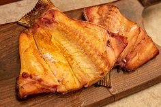 two pieces of fish on a wooden cutting board