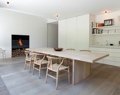 a dining room table with chairs and a fire place in the back wall behind it