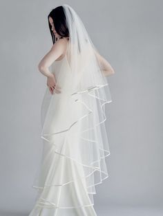 a woman in a wedding dress with a veil on her head and the back of her gown