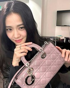 a woman holding a pink purse in front of her face and looking at the camera