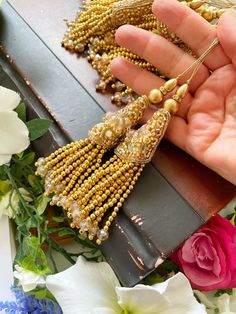 a person is holding some beads in their hand next to flowers and other things that are on the table