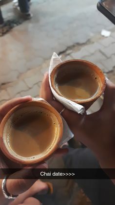 two people holding cups of coffee in their hands