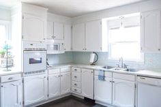 a kitchen with white cabinets and appliances in it