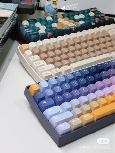 three different colored keyboards sitting on top of a desk