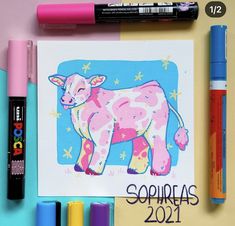 some crayons and markers are next to a drawing of a cow on a sheet of paper