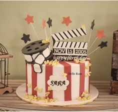 a birthday cake decorated with movie claps and popcorn on a table next to a birdcage