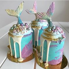 there are two cakes decorated with mermaid tail decorations on top of each other, one is blue and the other is pink