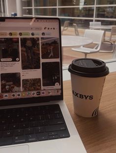 an open laptop computer sitting on top of a wooden table next to a cup of coffee